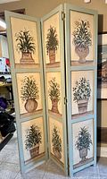 Full view of the 3-panel room divider painted with botanical pot designs on one side.