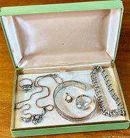Box of vintage sterling silver jewellery pieces arranged in a green box with cream coloured lining