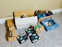 Boxes with various home improvement supplies including light bulbs, plumbing parts, and hardware.