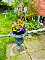 Full front view of cast iron urn planter with flower arrangement on patio
