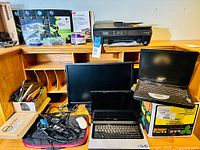 Overview of laptops, monitors, printer, accessories on desk excluding the desk itself.