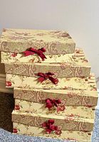 Stacked four floral fabric boudoir boxes with red bows on lids