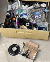 Full drawer view showing various plumbing parts including pipes, fittings and hoses packed together.