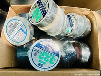 Box of mixed silver and black brand new duct tape rolls, several labeled 3M 322, all wrapped in plastic.