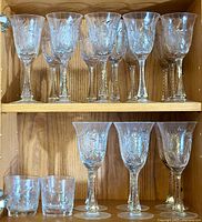 Wide view of three rows of etched glasses showing the different sizes and etched botanical designs.