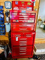 Full frontal view of two-piece red metal tool box on wheels showing top chest and bottom cabinet.