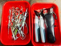 Top view of red trays with hair cutting scissors and electric hair clippers.