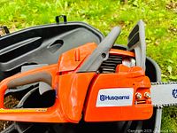 Side view of orange Husqvarna chainsaw inside black case