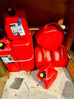 View showing six red plastic jerry cans stacked in storage, some with Scepter brand labels.