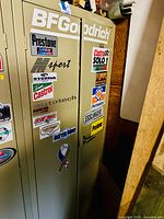 Closed beige metal cabinet with BFGoodrich and other automotive stickers on front