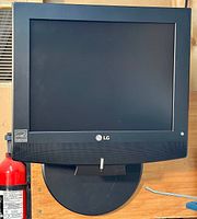 Front view of black LG flat screen TV mounted on wall mount, showing TV screen and LG logo on bezel.