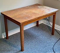 Full view of teak wood dining table showing rectangular top, legs, and worn surface