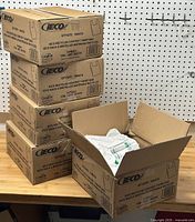 Five stacked cardboard boxes labeled IECO with one open box showing white plastic bags