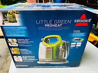 Box front showing Bissell Little Green ProHeat portable cleaner, features including permanently removes stains and odours, powerful spot and stain cleaning, Heatwave Technology, and branded Oxy stain remover formula.