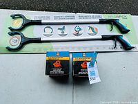 Photo of two grabber sticks with ergonomic handles and side magnets on packaging along with two suction cup dent pullers in boxes.