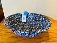 Side angle view of the large blue and white floral serving bowl, showing its oval shape and dense floral pattern.