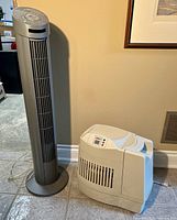 Photo of Seville Classics tower fan and white humidifier placed on floor against wall.