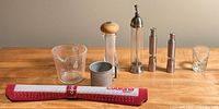 Whole lot with 4 pepper mills, glass measuring cup, small metal container, glass shot glass, and roll of cooking parchment paper