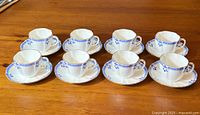 Full set of 8 tea cups with matching saucers arranged on wooden table