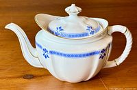 Large white bone china tea pot with blue floral border pattern and gold trim, side angle