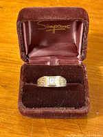 Ring centered in burgundy velvet display box showing front elevation