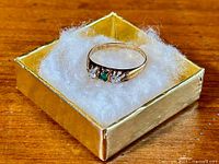 Ring resting on gold display box with white padding viewed from above