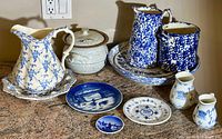 Full overview of the porcelain collection including pitchers, plates, and casserole dish on granite counter.