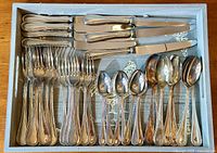 Full set of knives, forks, tablespoons, and teaspoons neatly arranged showing the complete assortment.