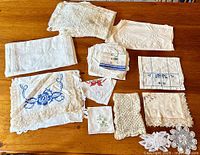 Overview of the vintage linen collection laid out on a wooden surface, showing various embroidered and crocheted pieces.