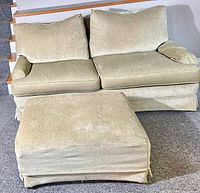 Front view of the loveseat couch with two seat cushions and two back cushions, showing the subtle greenish-grey fabric and light wear.