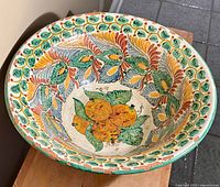 Top-down photo showing overall interior decoration with fruit and leaf motifs on the vintage Mexican redware bowl.
