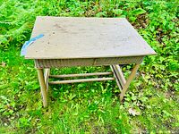 Photo showing the wooden top with a few marks and light weathering, the wicker sides and legs visible.