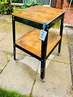 Work bench front and side view showing metal frame, wooden surfaces and wheels