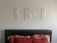 Wide view of the three-panel bamboo motif wall art set mounted above a headboard, showing arrangement and general appearance.