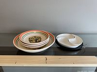 Three ceramic pasta bowls stacked together showing colorful vintage-style pasta print and borders.