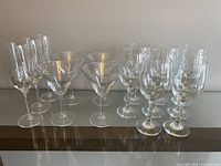 The full set of clear glassware arranged on a glass surface showing 3 champagne flutes, 4 martini glasses, and 8 wine glasses in rows.