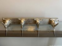 Front view of metal wall hook rack with silver rhinoceros head hooks mounted on backplate.
