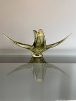 Front view of the olive green vintage art glass sculpture showing its symmetrical wing-like extensions and rounded base.