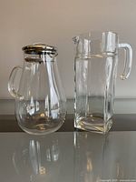 Two pitchers side by side: one rounded with metal strainer lid, one tall rectangular without lid