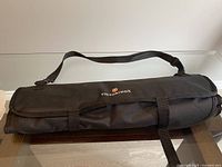 Closed black fabric utensil roll with Victorinox branding and adjustable shoulder strap, showing minor surface wear.