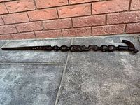 Two pieces of a dark wooden carved African walking stick showing detailed hand-carved designs and an animal head handle, broken in half.
