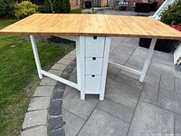 Table open with both leaves extended, showing butcher block top and central drawer pedestal