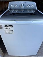 Front view of GE top-load washing machine showing white cabinet, tinted glass lid, control panel and EnergyGuide label.