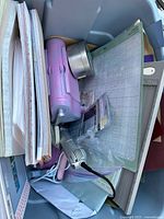 Top view of craft bin contents showing paper pads, Cuttlebug embosser, glue tool, metal tin and cutting mats.