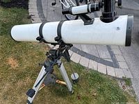 Side view of white telescope tube mounted on equatorial mount and tripod with counterweight
