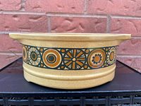 Side view showing beige speckled ironstone with a decorative band featuring mid-century geometric patterns in black, mustard yellow, and brown.