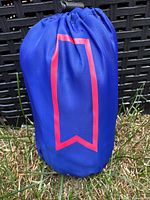 Blue drawstring pouch containing the running jacket, featuring a red geometric design element on the pouch