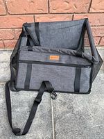 Front angle of the grey dog car booster seat showing black straps and zipper pocket on the exterior