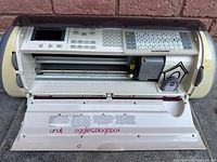 Front open view of the Cricut cutting machine showing control panel and cutting blade area, used condition with some decorations and visible wear.