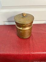 Closed antique brass canister with lid showing patina and some oxidization.